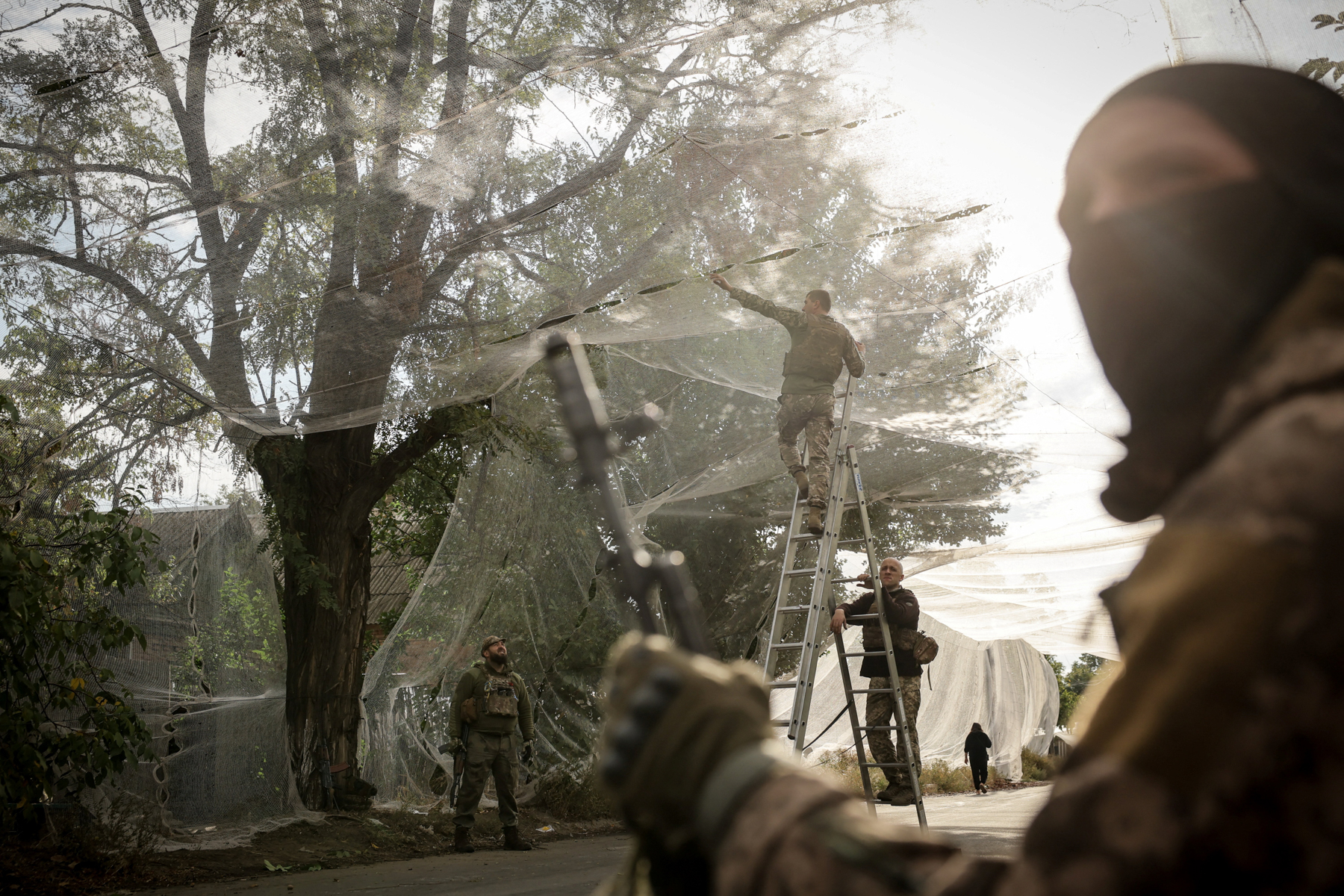 Ukrainian military personnel install anti-drone nets over a road in the frontline town of Konstantinovka, Donetsk region, Ukraine